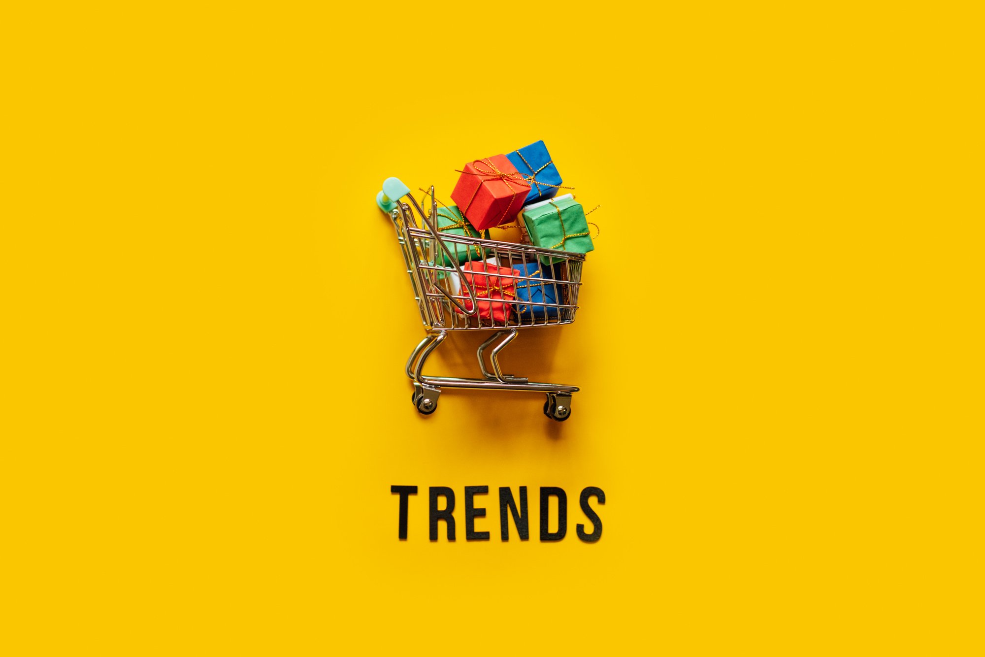 Ecommerce Retail Shopping trends concept. Word Trends and mini shopping cart with box on yellow background.